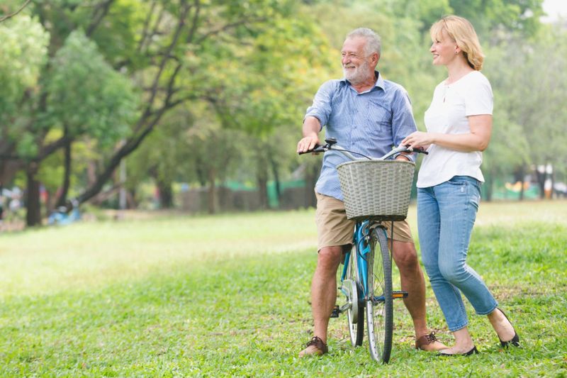 Happy elderly mortgage broker riding bicycle beside daughter