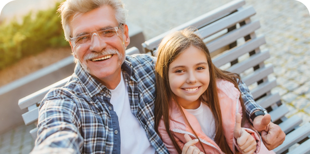 BC grandfather sitting on park bench with smiling granddaughter