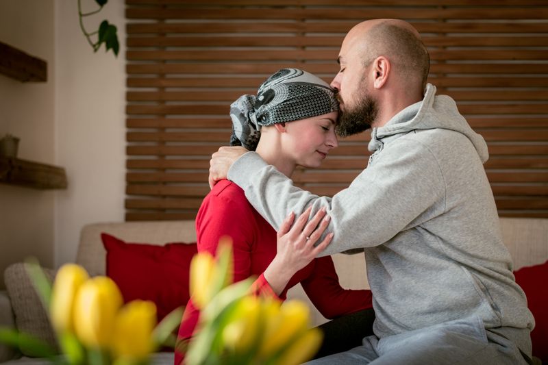Supportive boyfriend embracing young cancer survivor