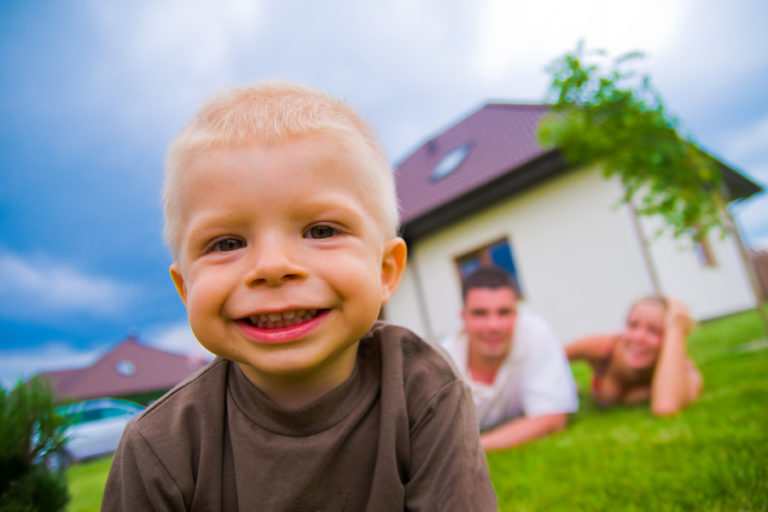 child smiling into camera with parents behind