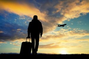Solo traveler with travel medical insurance watching a plane fly at sunset