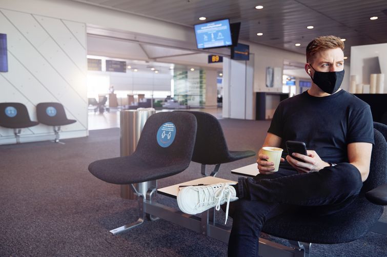 Health-conscious man holding phone and coffee while seated in airport