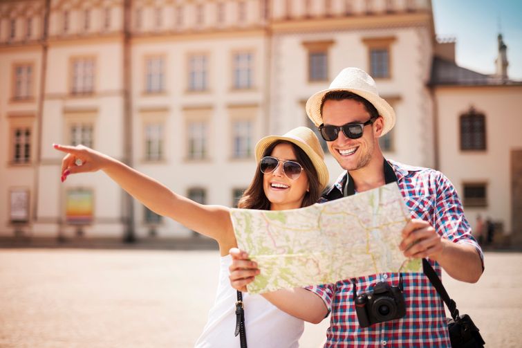 Happy tourist couple reading a map in European square