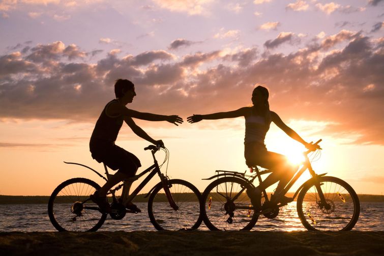 Satisfied couple taking an evening bike ride on BC beach