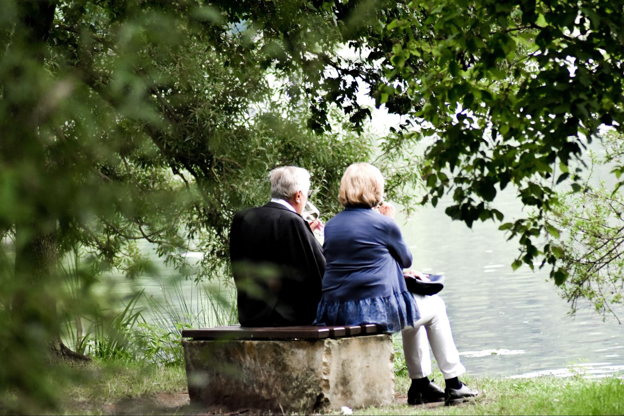 senior couple sitting on bench looking out to water