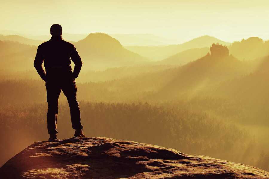 person standing in a sunset on the mountains